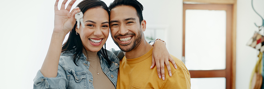 A happy couple shows off the keys to their first home