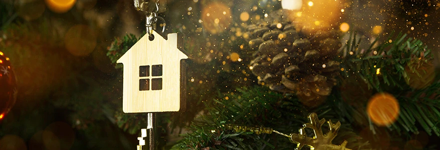 A home shaped ornament sits on a Christmas tree